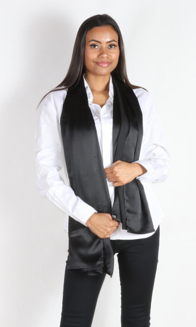 A 6 ft tall female model gracefully displays Aviator silk scarf in black draped from her neck - 100% Plant Based Scarf Made From Rose Plant Yarn.