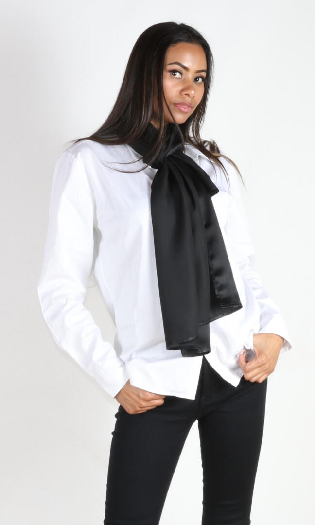 A 6 ft tall female model gracefully displays Aviator silk scarf in black tied around her neck - 100% Plant Based Scarf Made From Rose Plant Yarn.