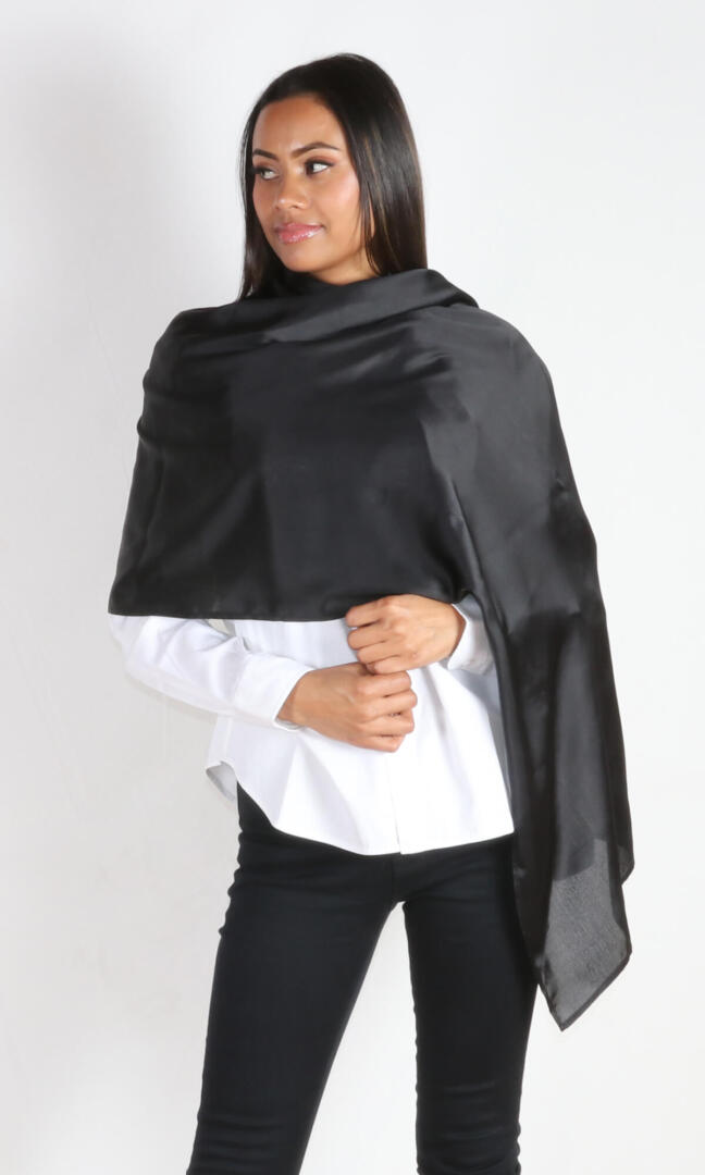 A 6 ft tall female model gracefully displays Aviator silk scarf in black wrapped around her body - 100% Plant Based Scarf Made From Rose Plant Yarn.