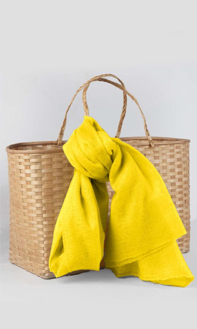 Detailed shot of the premium handwoven 100% pure Buttercup Yellow cashmere shawl - tied to the handle of the traditional bamboo gift basket.