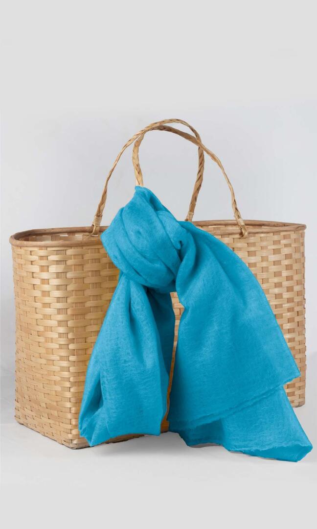 Detailed shot of the premium handwoven 100% pure Celeste Blue cashmere shawl - tied to the handle of the traditional bamboo gift basket.