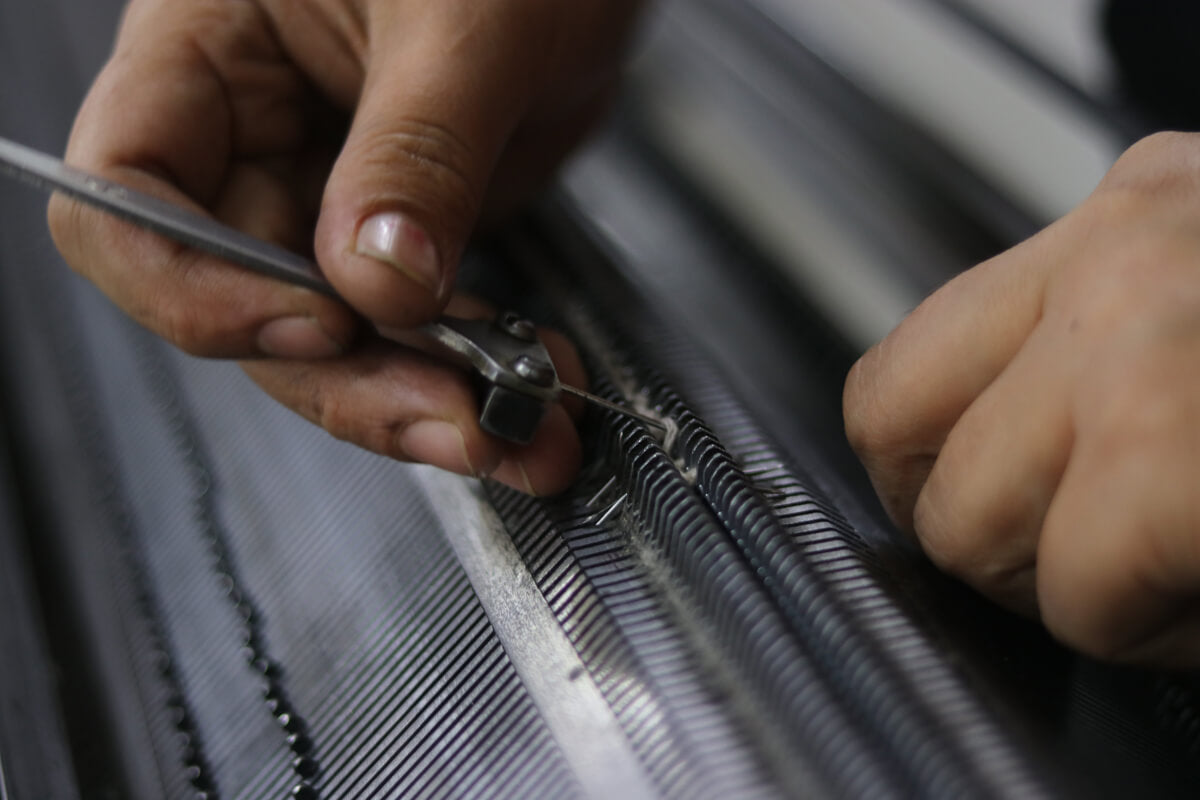 A woman artisan adjusts the cashmere yarns to the correct gauze before knitting begins.