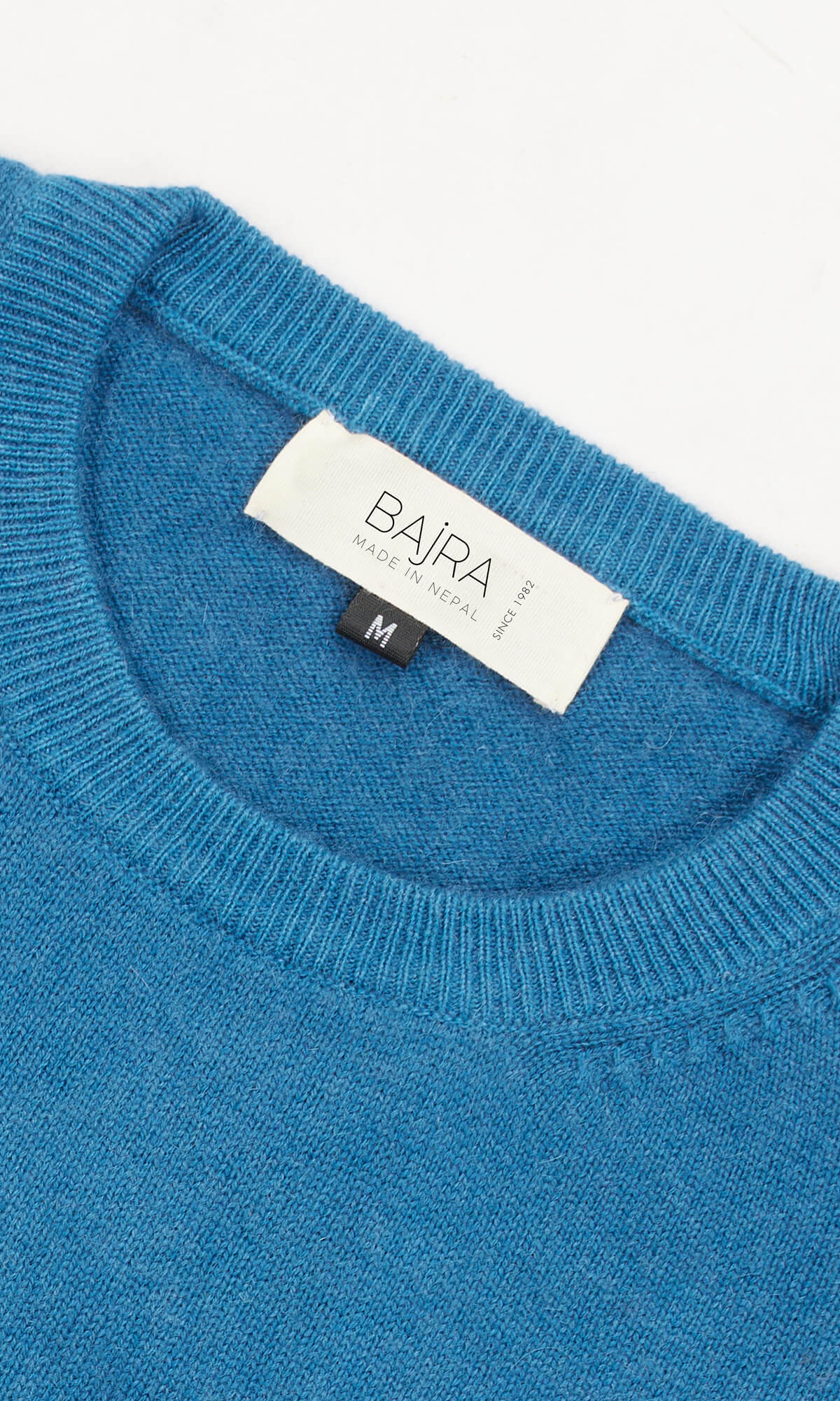 A Sapphire Sky Pure Cashmere Cardigan Long Sleeve Pullover showing the close-up view of the ribbed roundneck ethically crafted in Nepal from sustainable sourced pure cashmere yarns.