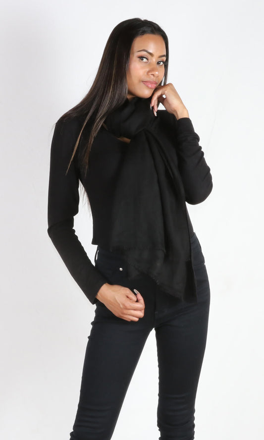 A 5ft 8 inches tall female model displays a 100% pure handmade black cashmere shawl tied around her neck as a neck scarf without being bulky.