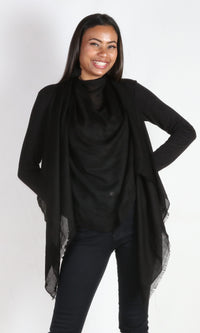 A 5ft 8 inches tall female model displays a 100% pure handmade black cashmere shawl tied around her neck and draped nicely in front of the body.