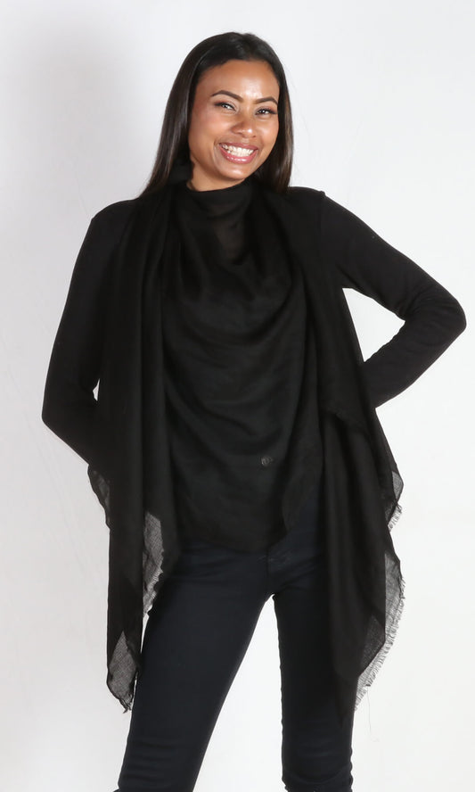 A 5ft 8 inches tall female model displays a 100% pure handmade black cashmere shawl tied around her neck and draped nicely in front of the body.