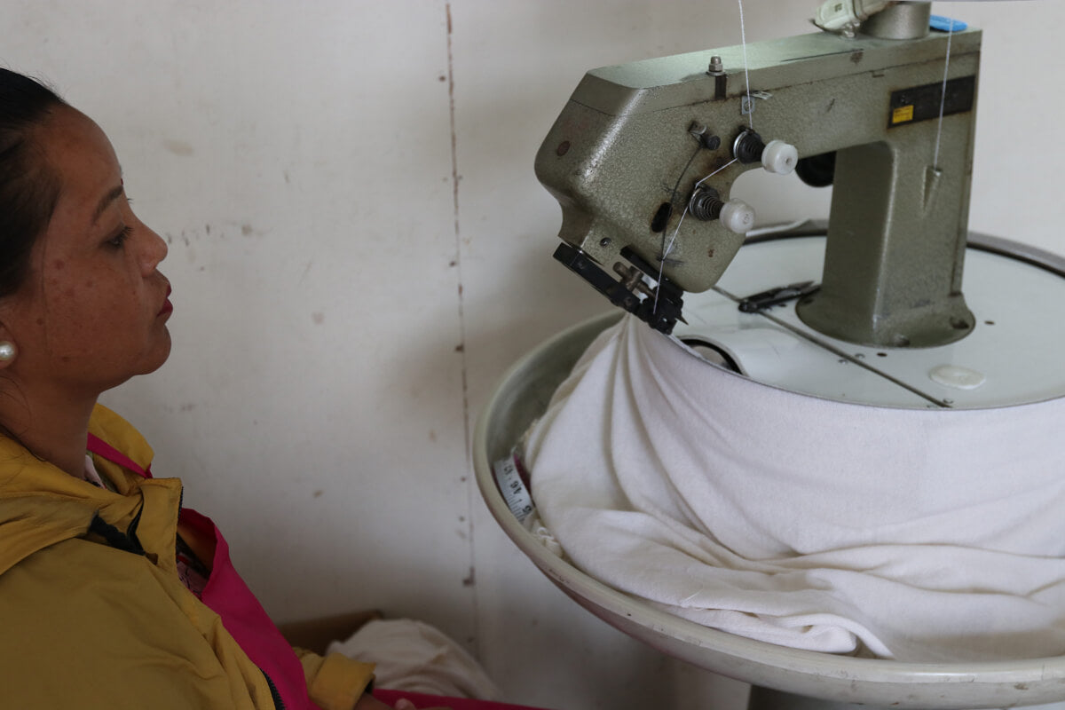 A woman artisan links the cashmere sweater panels after being knitted.