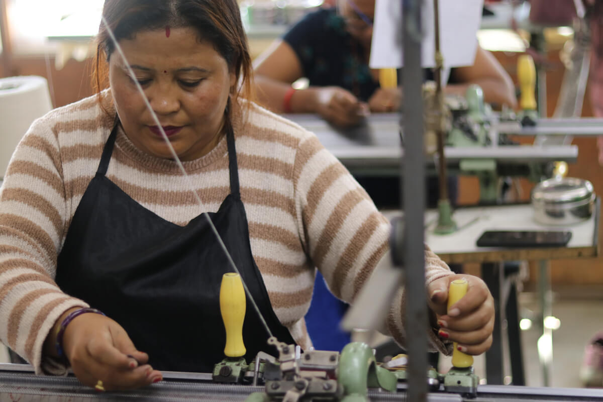 A woman artisan operates the semi-automatic knitting machines to make cashmere sweaters.