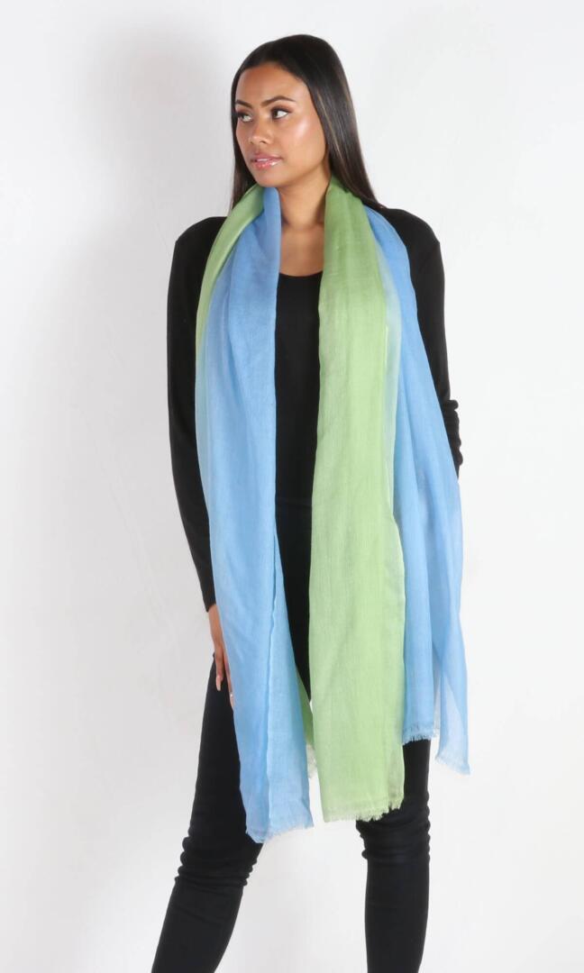 A beautiful model drapes the super light two-color cashmere car shawl, an extra large wrap, around her neck as a long scarf.