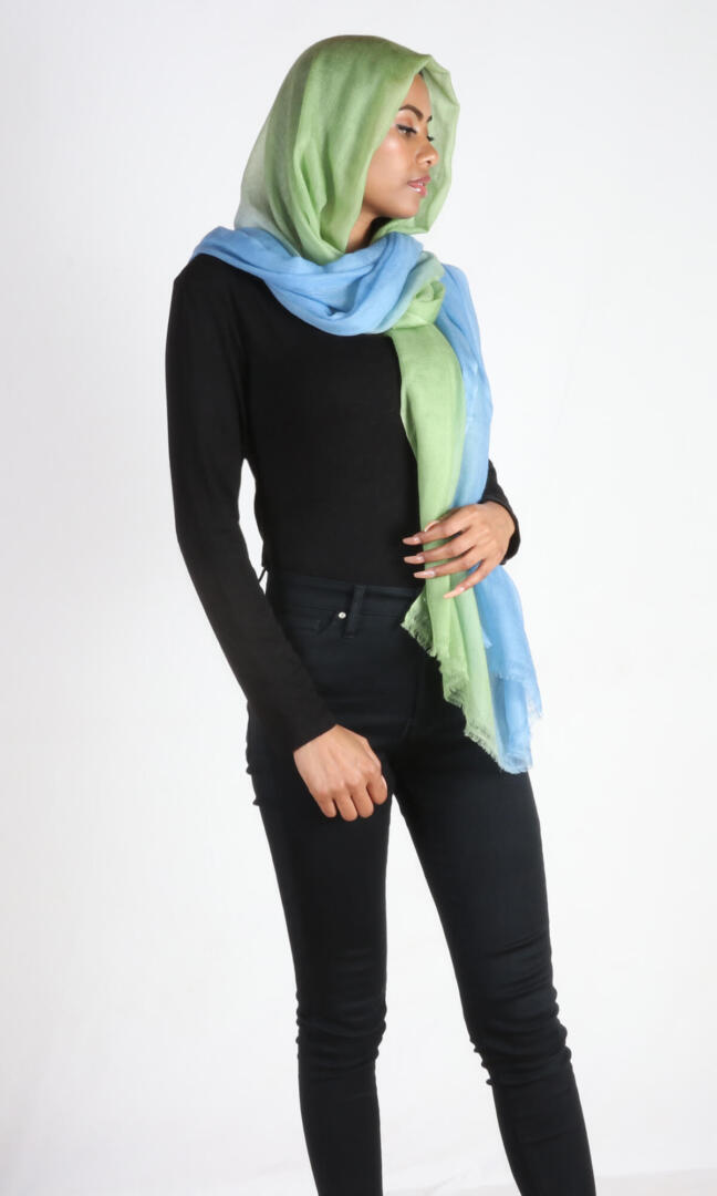 A beautiful model with a super light two-color cashmere car shawl drapes beautifully over her head.