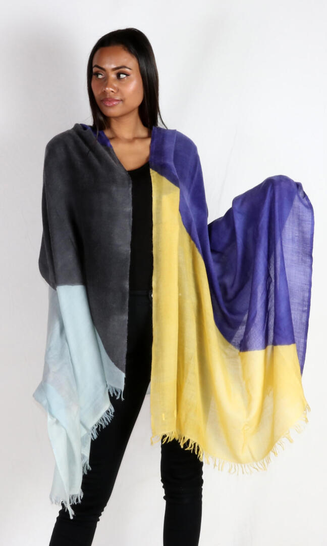 A beautiful model spreads the stunning and eye-catching super lightweight cashmere romance shawl to display its four colors, Aquamarine, French Blue, Charcoal, and Yellow.