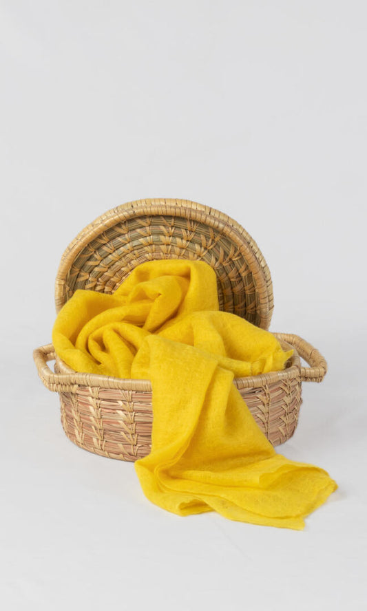 A detailed view of handwoven 100% Pure Emperor Yellow Cashmere Shawl in a hand-weaved basket with lid to display the elegance cashmere carries.