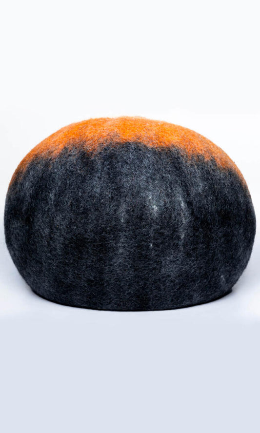 A handmade cat hideaway in the shape of an oval with a round entrance in black, deep orange, and white, with a back view.