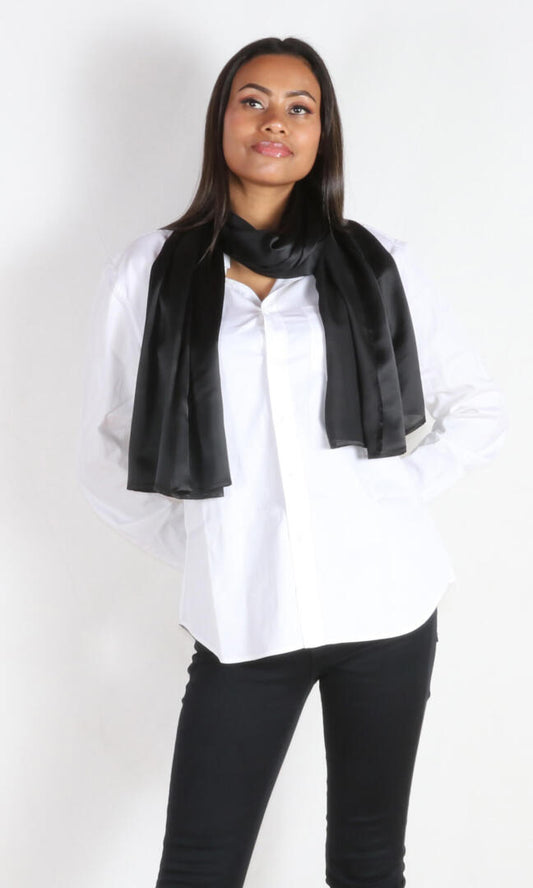 A 6 ft tall female model gracefully displays Aviator silk scarf in black draped around her neck - 100% Plant Based Scarf Made From Rose Plant Yarn.