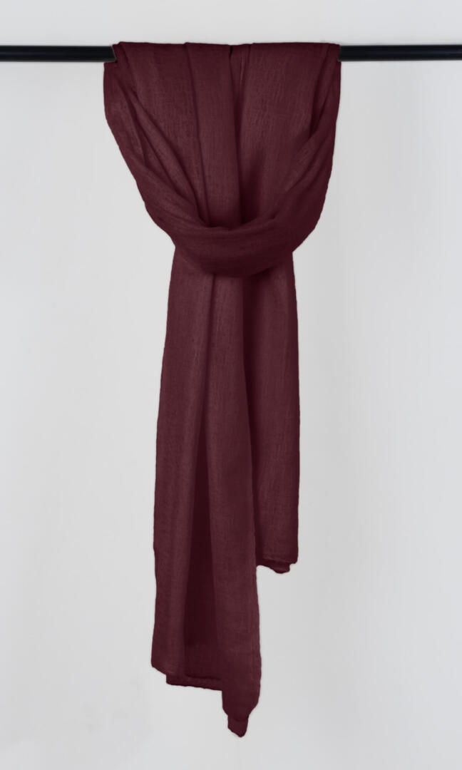 Full view of the premium handwoven 100% pure Dark Burgundy cashmere shawl hanging from a bar to display its silhouette.