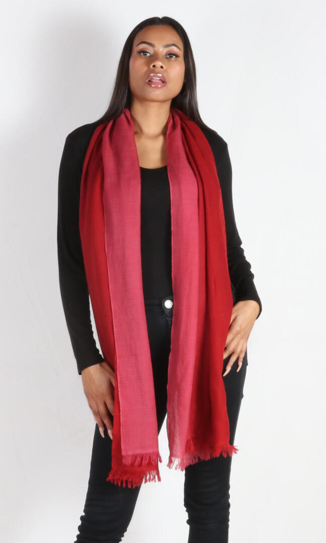 A female model displays a handmade two-tone red cashmere shawl draped around her neck as evening scarf.