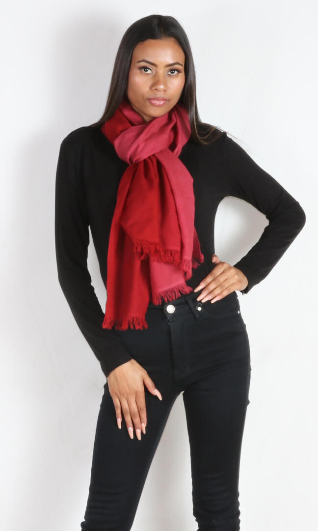 A female model displays a handmade two-tone red cashmere shawl wrapped around the neck as a scarf.