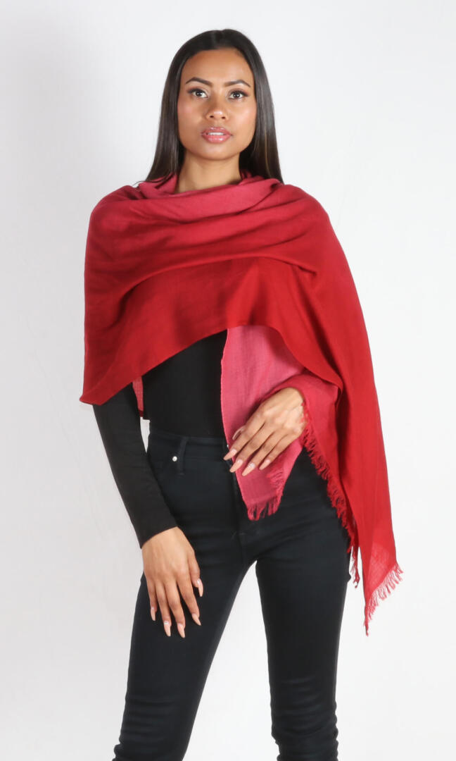 A female model displays a handmade two-tone red cashmere shawl wrapped around the shoulders as a wrap.